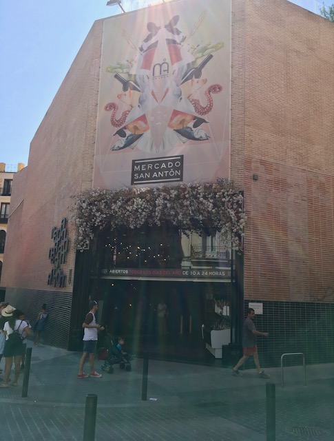 The exterior of the Mercado San Anton features a beautiful mural and flowers over the entry way. 