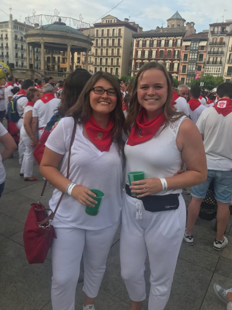 Participants dressed entirely in white with red buffs celebrate La Fiesta de San Fermín with the masses of people. 